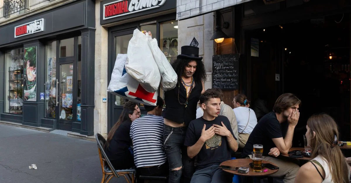 Des gens savourant des boissons dans un café urbain à côté d'un magasin de bandes dessinées sur une rue de la ville.