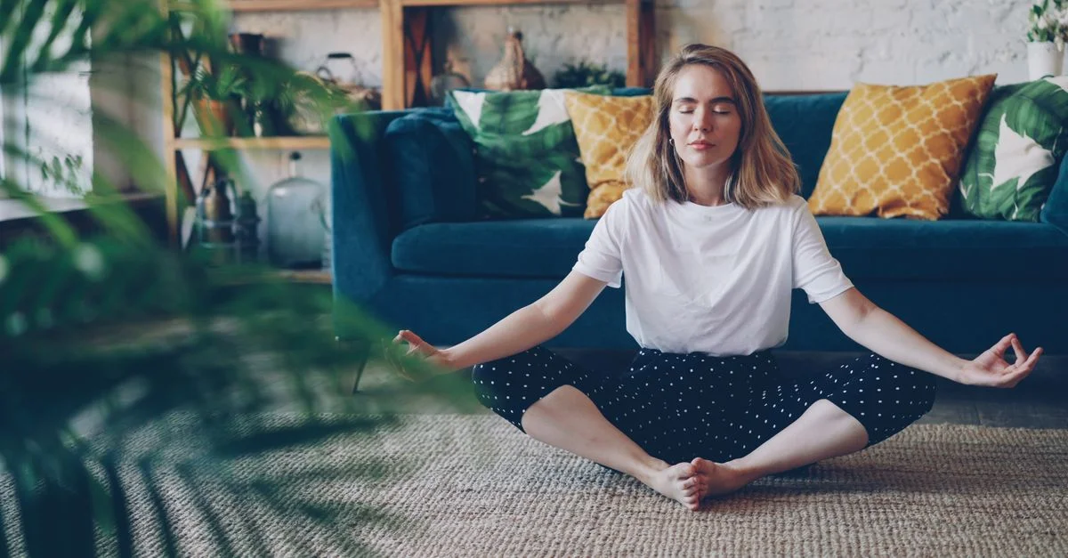Femme méditant dans un salon confortable, mettant l'accent sur la détente et la pleine conscience.